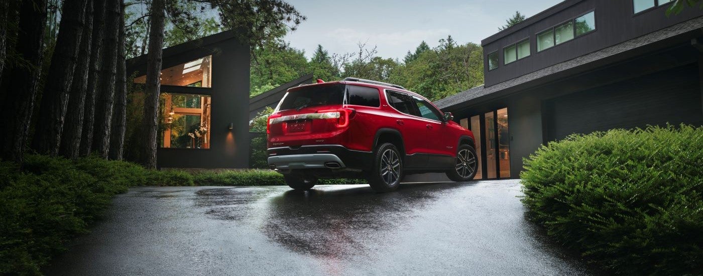 Red 2022 GMC Acadia parked on a wet driveway