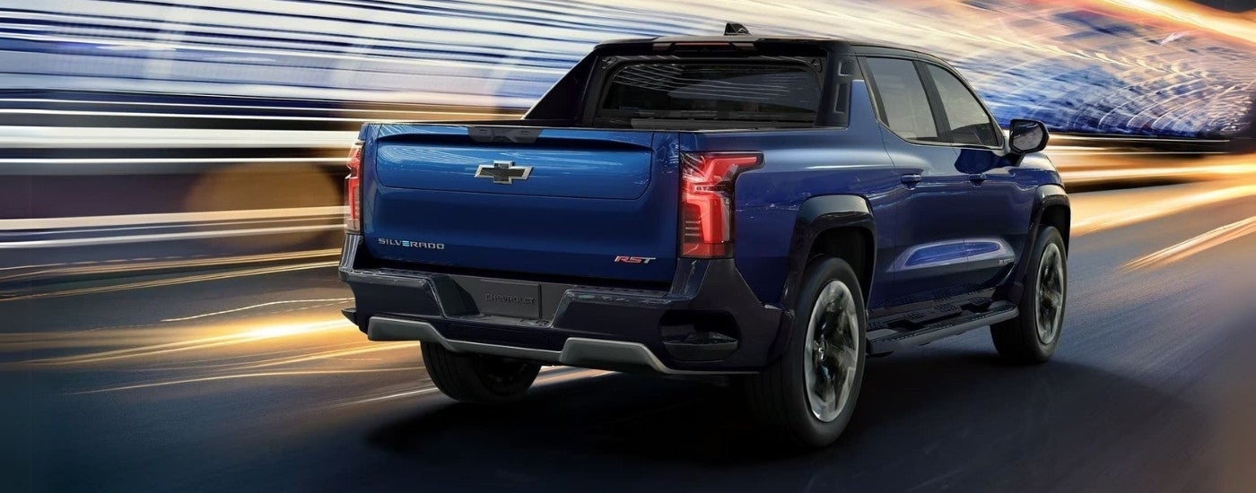 A blue 2024 Chevy Silverado EV RST is shown from behind speeding through a tunnel.