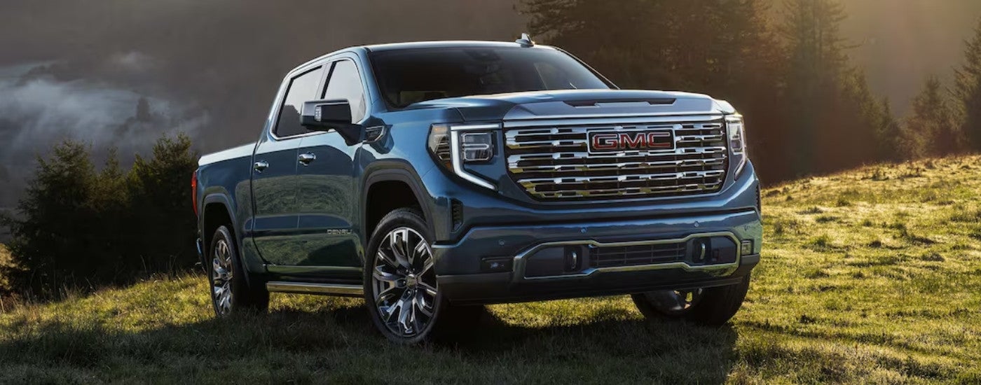 Blue 2025 GMC Sierra 1500 parked off-road on a hill.