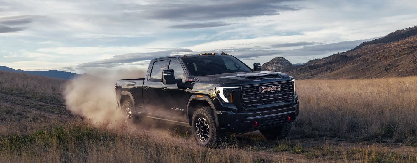 Black 2026 GMC Sierra 2500 HD AT4X driving on a dusty trail