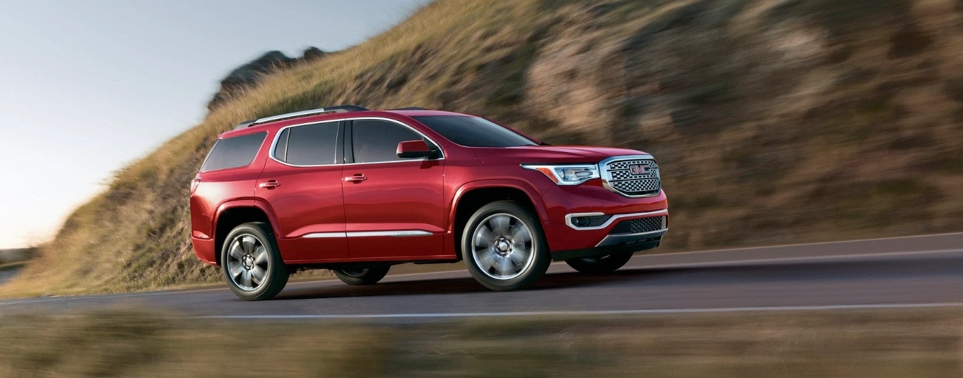 A red 2017 GMC Acadia driving up a mountain.