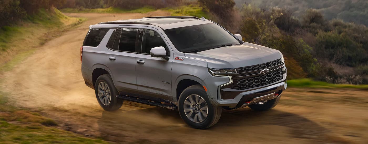 A grey 2024 Chevy Tahoe Z71 driving around a dirt bend.