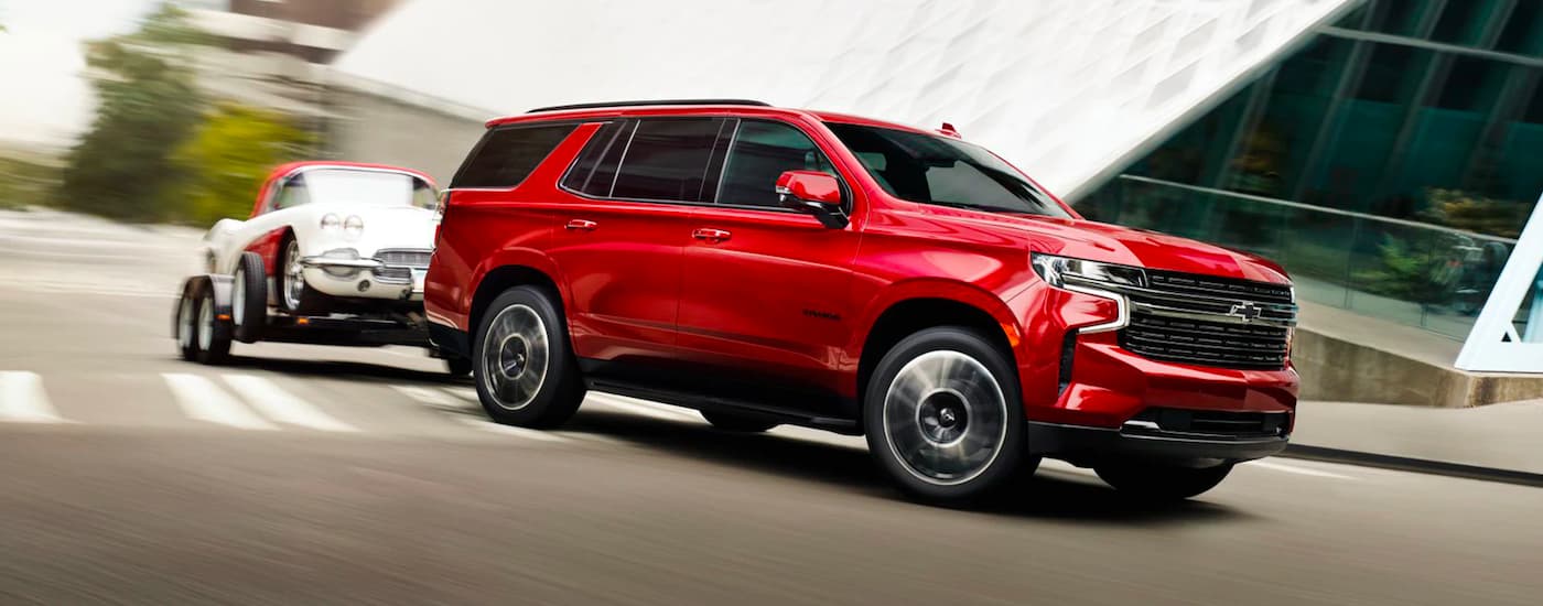 Red 2025 Chevy Tahoe towing a vehicle around a bend.