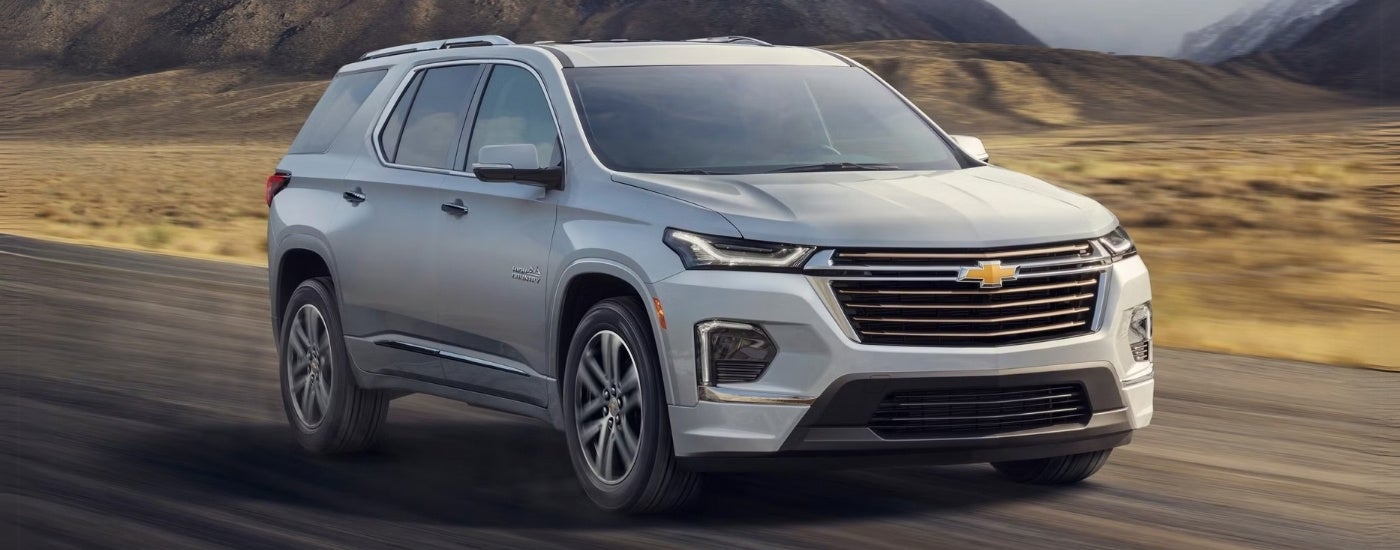 A silver 2022 Chevy Traverse High Country driving on an empty highway.