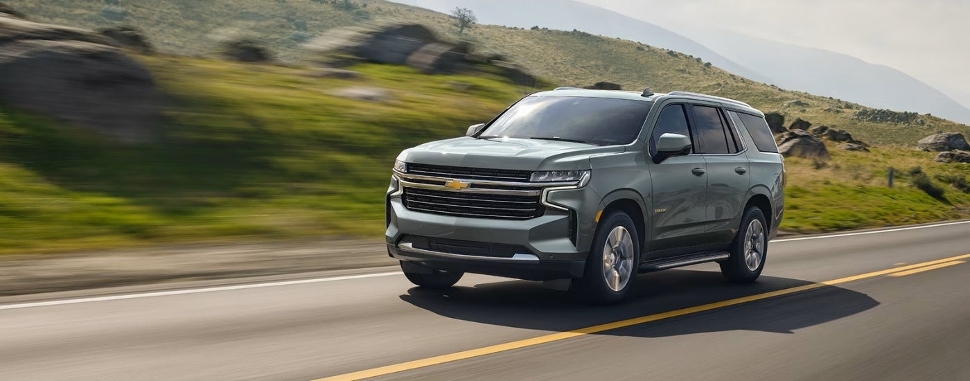 A grey 2022 Chevy Tahoe is shown driving on an open road.