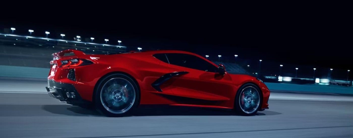 A red 2023 Chevy Corvette 3LT Z51 is shown from the side on a race track at night.