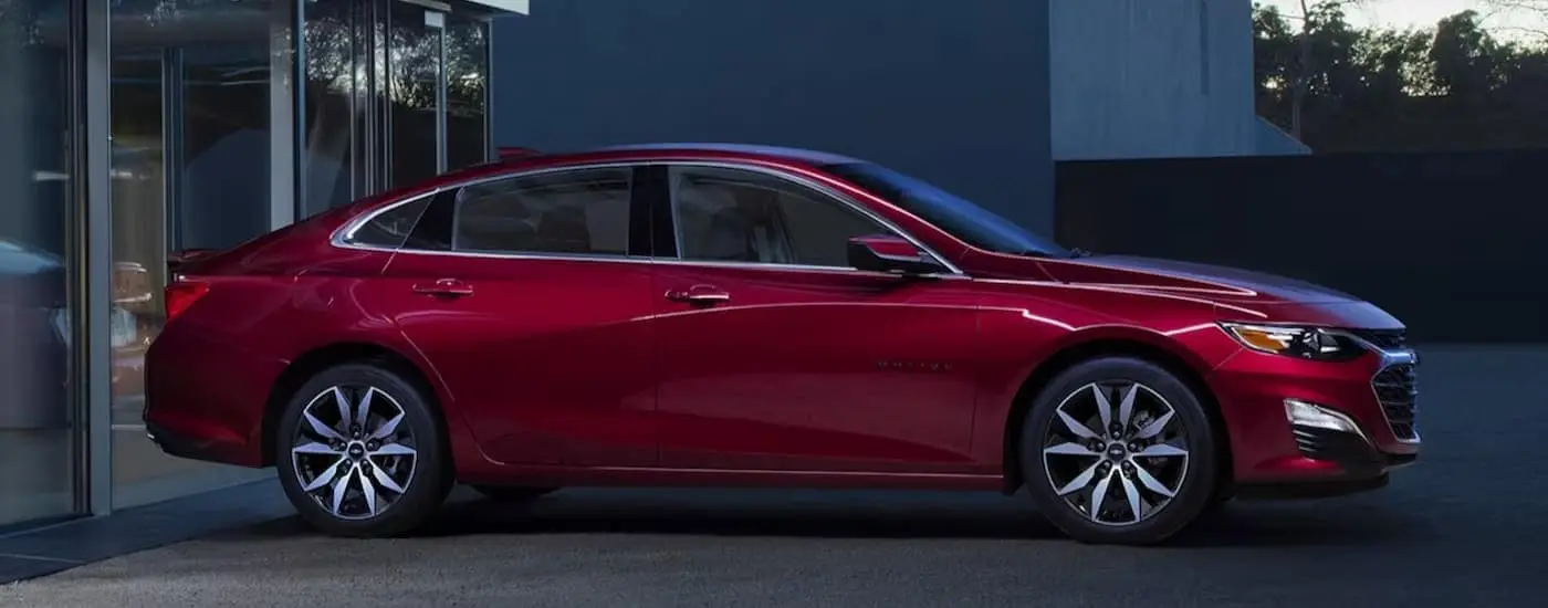 A red 2024 Chevy Malibu RS is shown parked on a driveway.