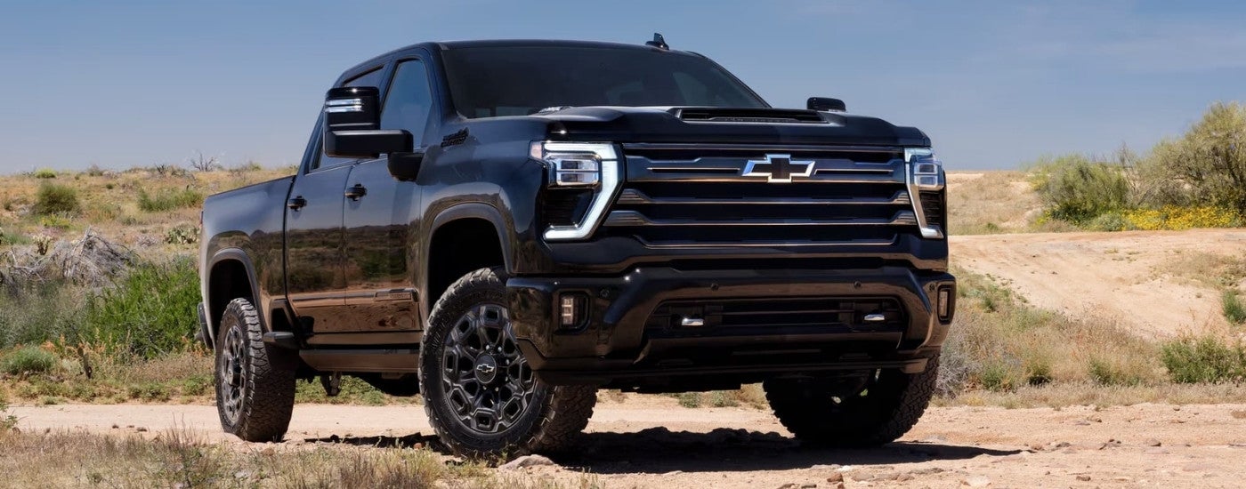 A black 2024 Chevy Silverado 2500 HD Midnight Edition is shown parked off-road.