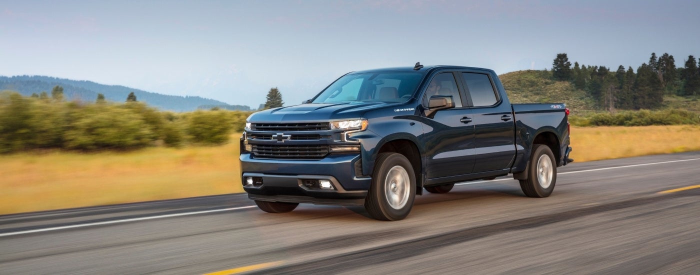 A blue 2020 Chevy Silverado RST is driving on an empty highway.
