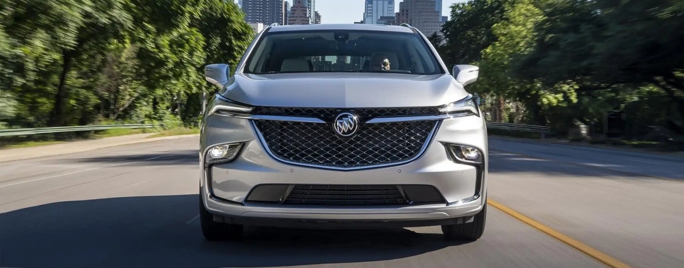 A silver 2022 Buick Enclave Avenir driving away from a city.