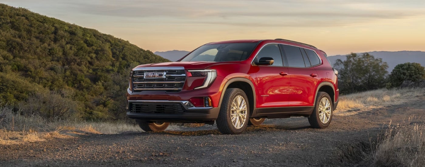 Red 2025 GMC Acadia driving to a GMC Acadia dealer