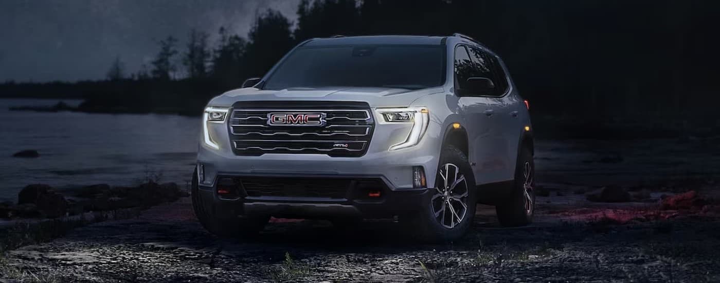 A white 2024 GMC Acadia AT4 parked at night.