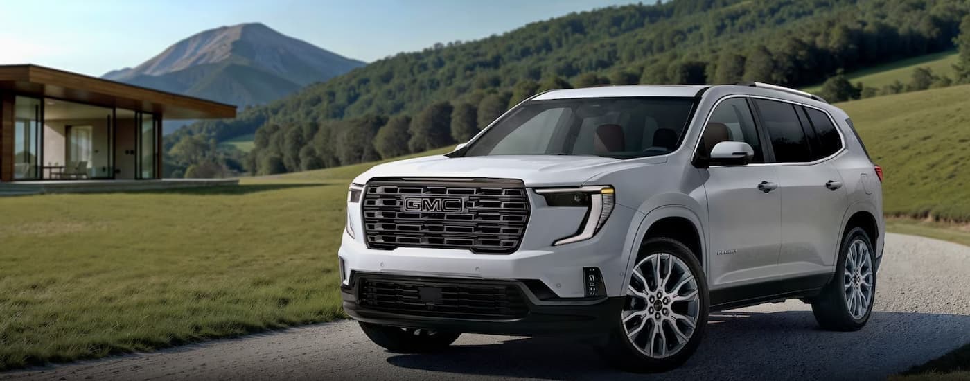 A white 2026 GMC Acadia parked near a house.