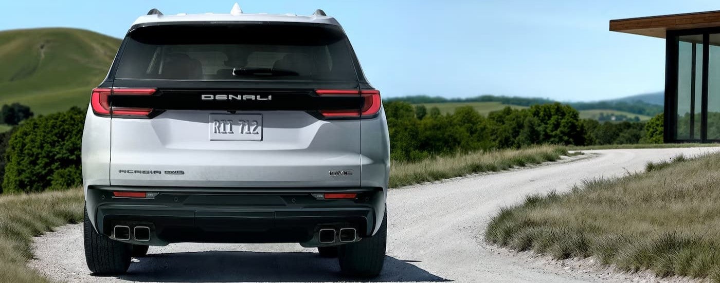A white 2026 GMC Acadia driving on a road.