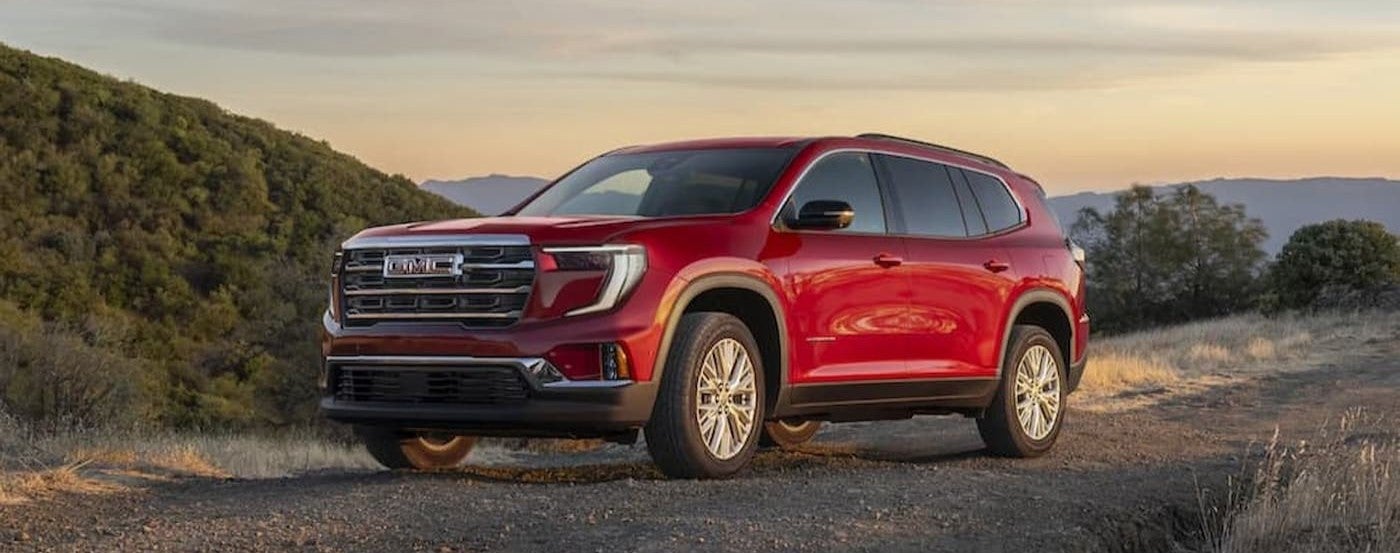 A red 2026 GMC Acadia parked offroad.
