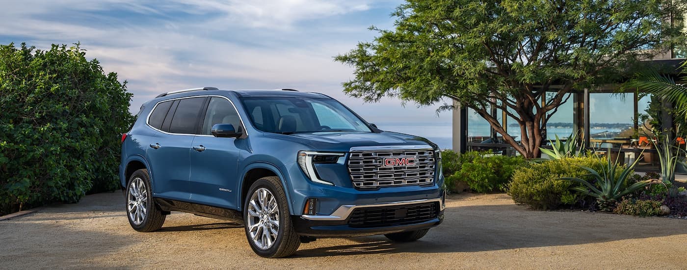 Blue 2025 GMC Acadia Denali parked outside a house after visiting a GMC dealer near Crump.