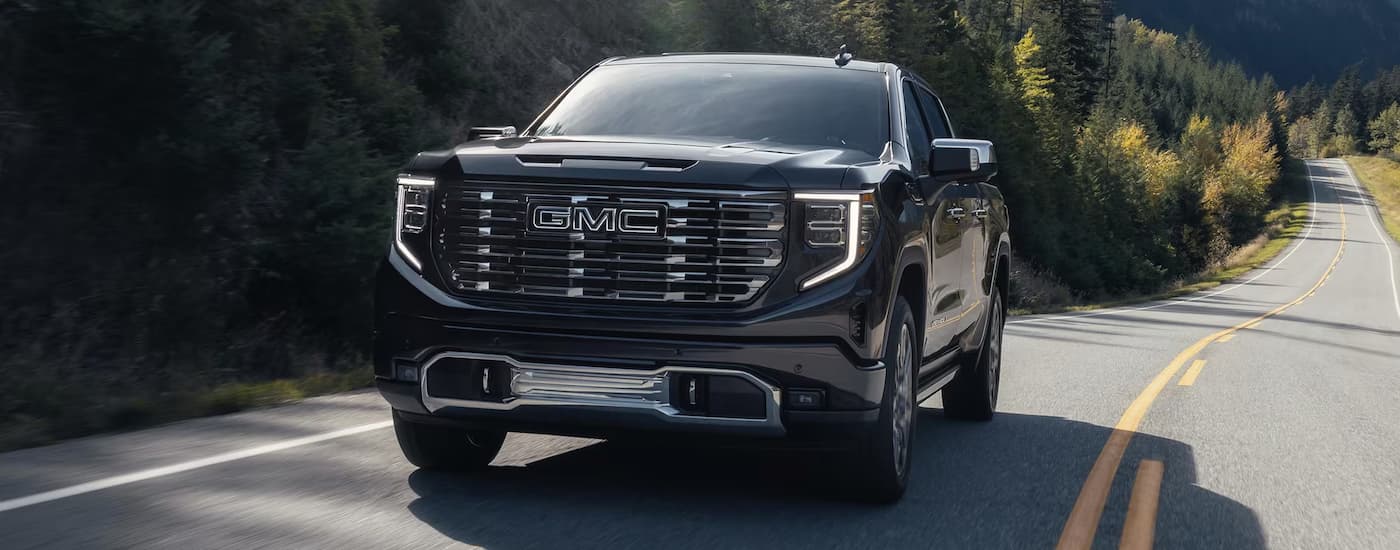 Black 2025 GMC Sierra 1500 Denali Ultimate driving down an open road.