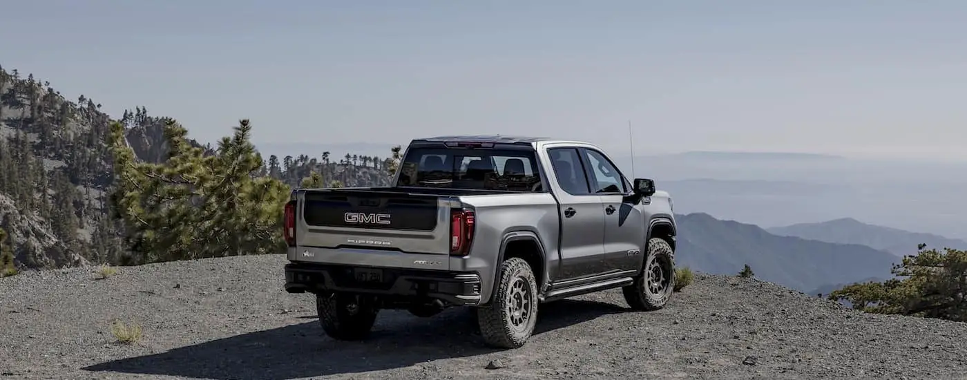 Silver 2024 GMC Sierra AT4x AEV is shown from the rear at an angle