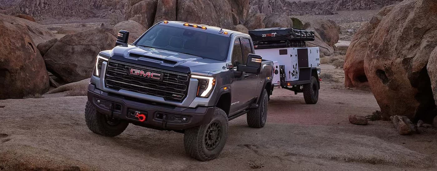 A gray 2025 GMC Sierra 2500 AT4X towing a trailer off-road.
