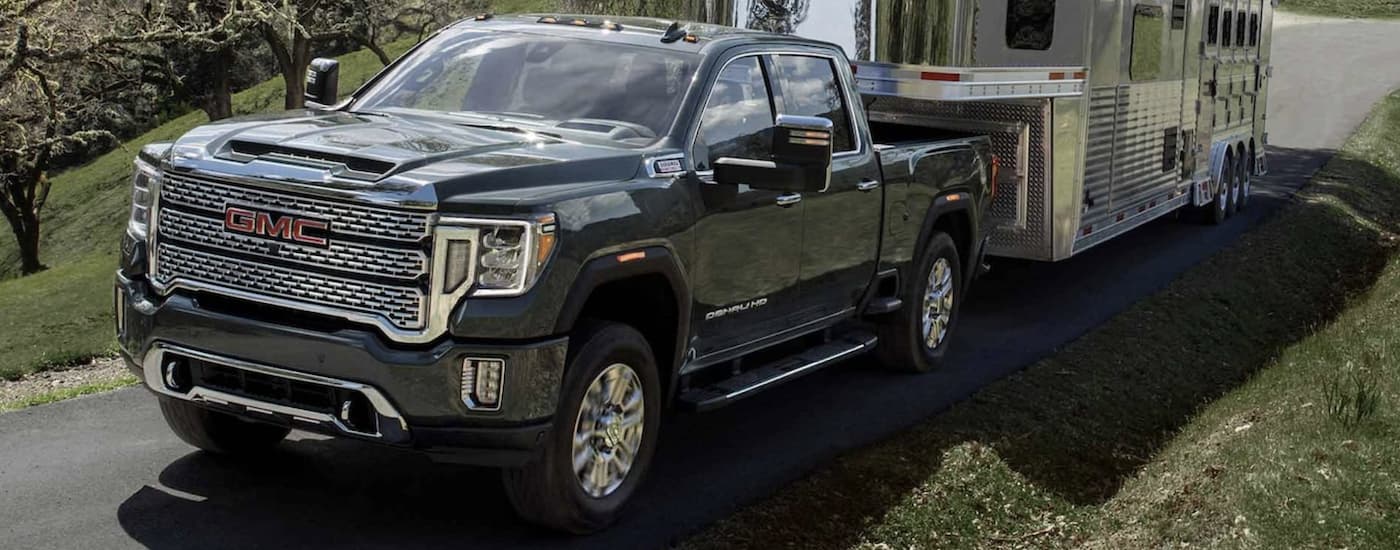 Black 2024 GMC Sierra 3500 HD towing a camper.
