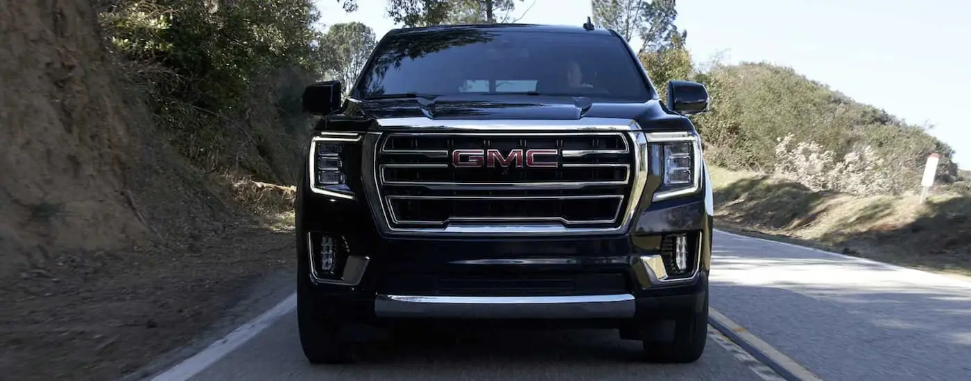 A black 2022 GMC Yukon is shown driving on a highway.