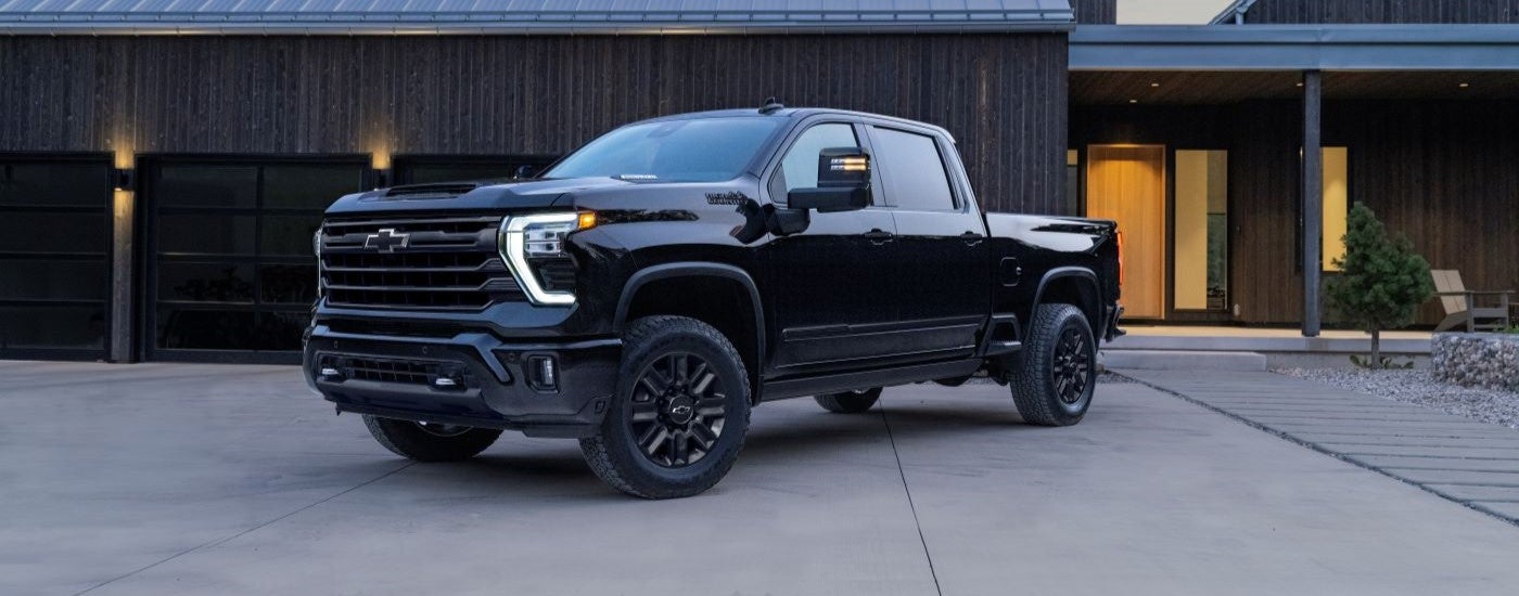 A black 2024 Chevy Silverado 2500 HD High Country Midnight Edition is shown parked on a driveway.