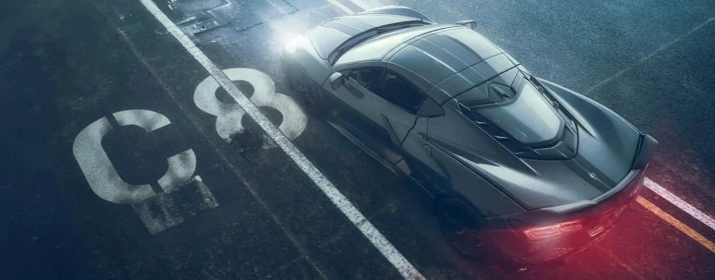 A grey 2022 Chevy Corvette is shown from a high angle driving over a lane painted with a white 'C8'.