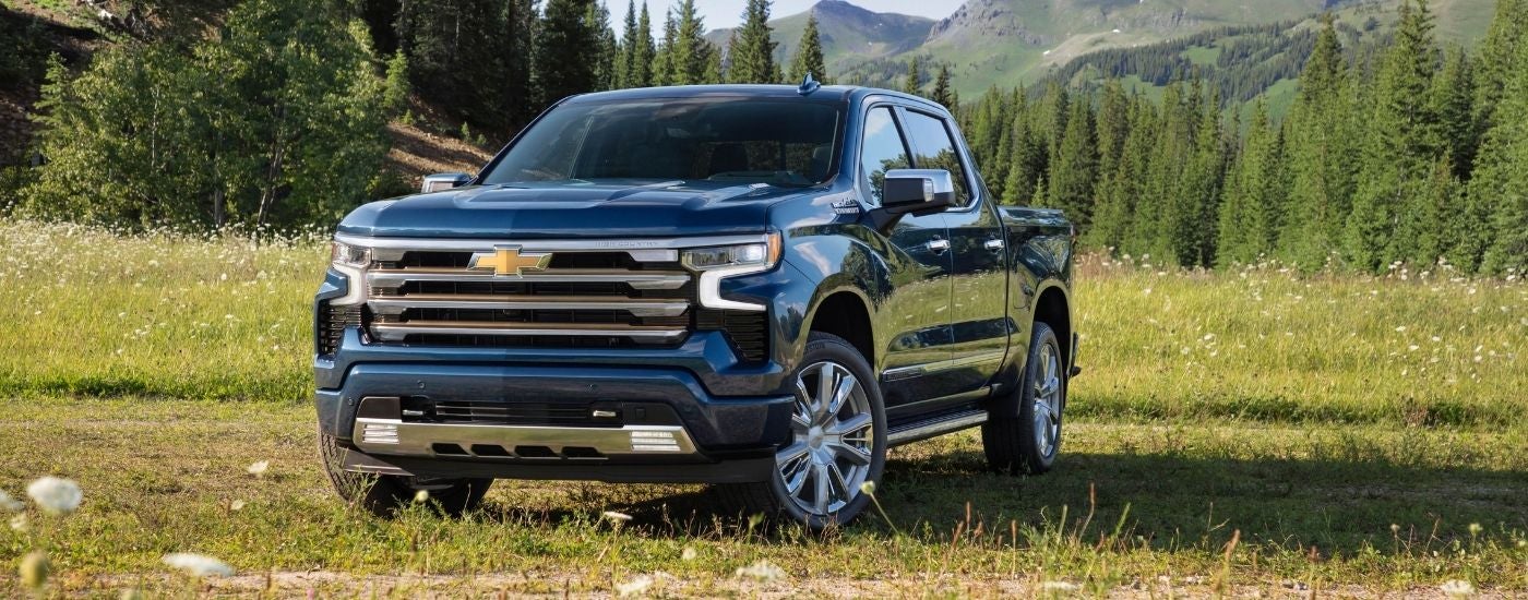 A dark blue 2022 Chevy Silverado 1500 High Country parked in a field after visiting a Selmer Silverado dealership.