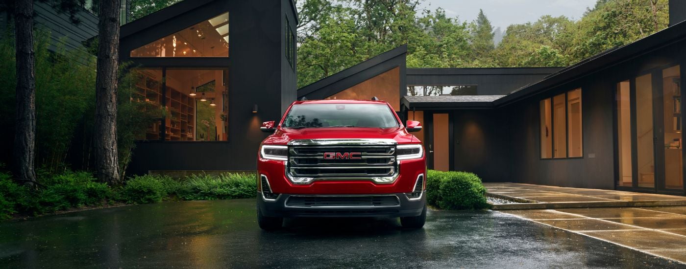 A close-up of the grille of a red 2021 GMC Acadia is shown.