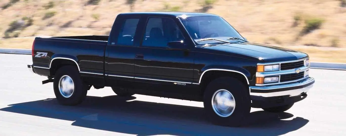 A black 1999 Chevy Silverado 1500 Z71 driving on an empty road.