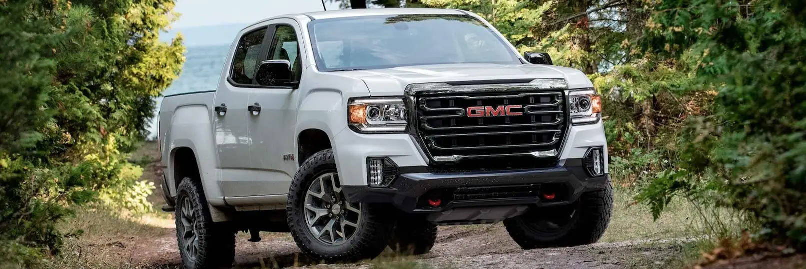 White 2022 GMC Canyon AT4 parked next to trees