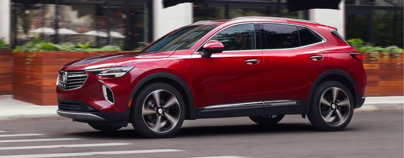 A red 2021 Buick Envision is shown driving on a city street after leaving a Buick dealer in MS.