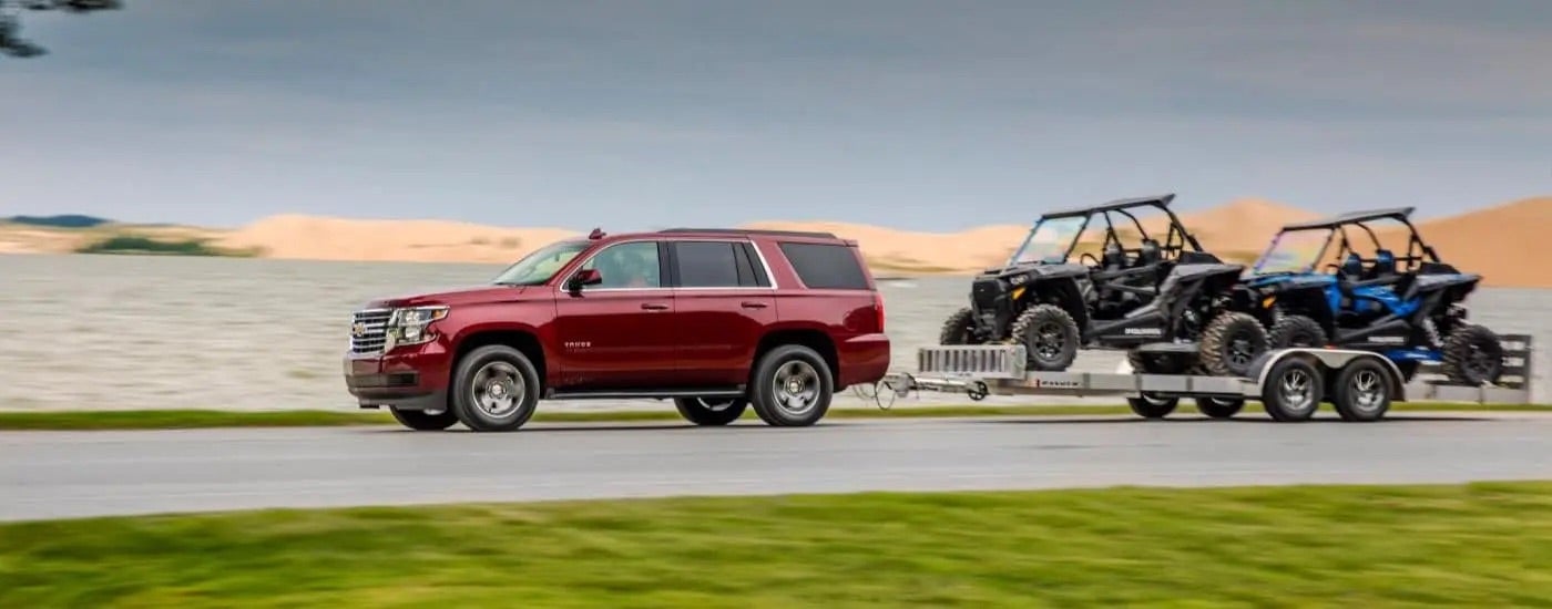 A red 2018 Chevy Tahoe towing ATVs.
