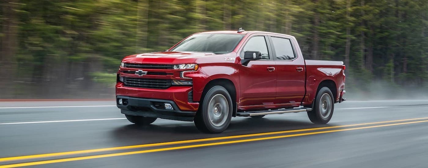 A red 2021 Chevy Silverado 1500 Z71 is shown driving on a highway to view a used Chevy Silverado for sale.