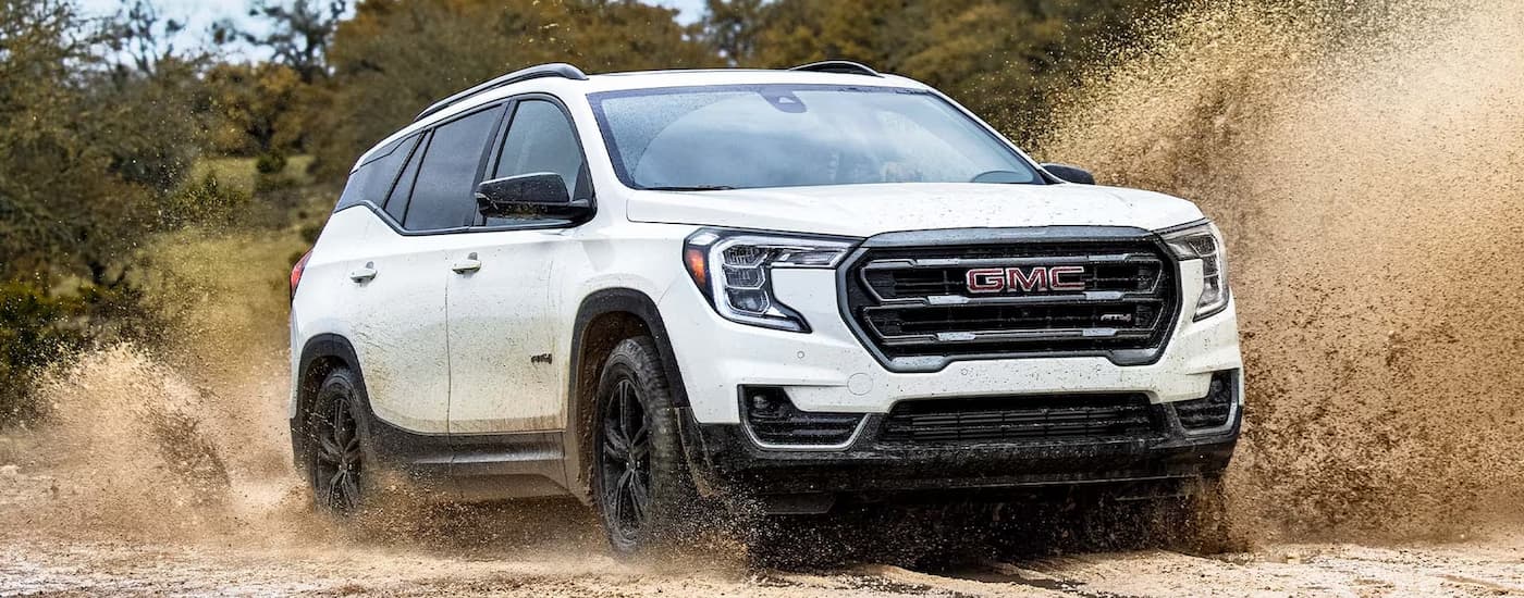 White 2024 GMC Terrain AT4 driving a used GMC dealer.