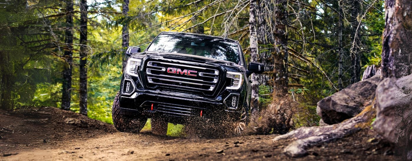 Black 2019 GMC Sierra 1500 driving off-road froma dealer with used GMC trucks for sale.