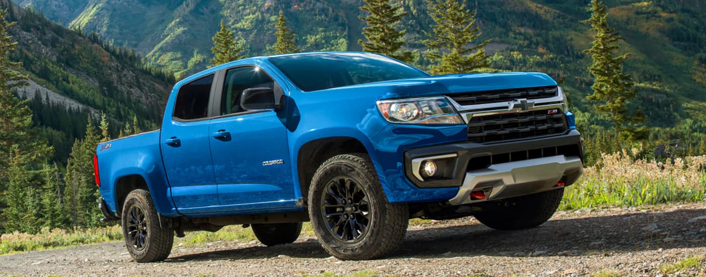 A blue 2022 Chevy Colorado driving on a dirt road in the mountains.