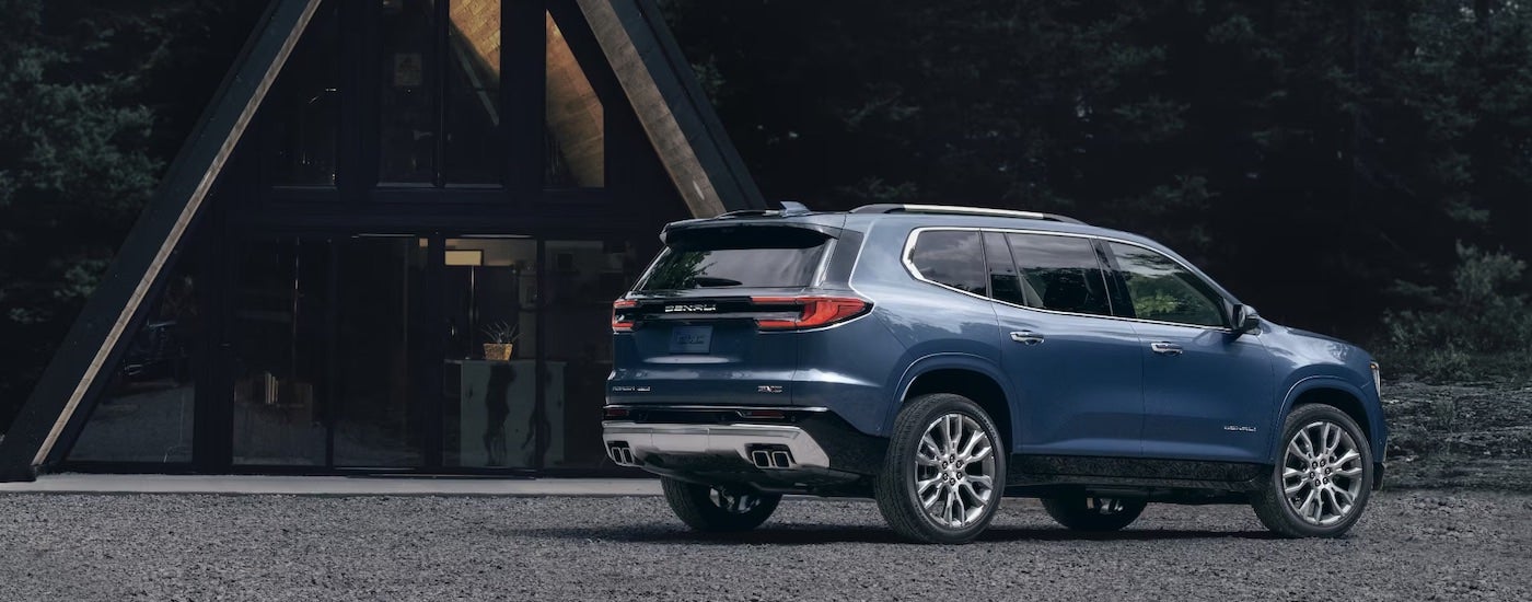 Blue 2024 GMC Acadia is shown from the rear at an angle after leaving a GMC Dealer