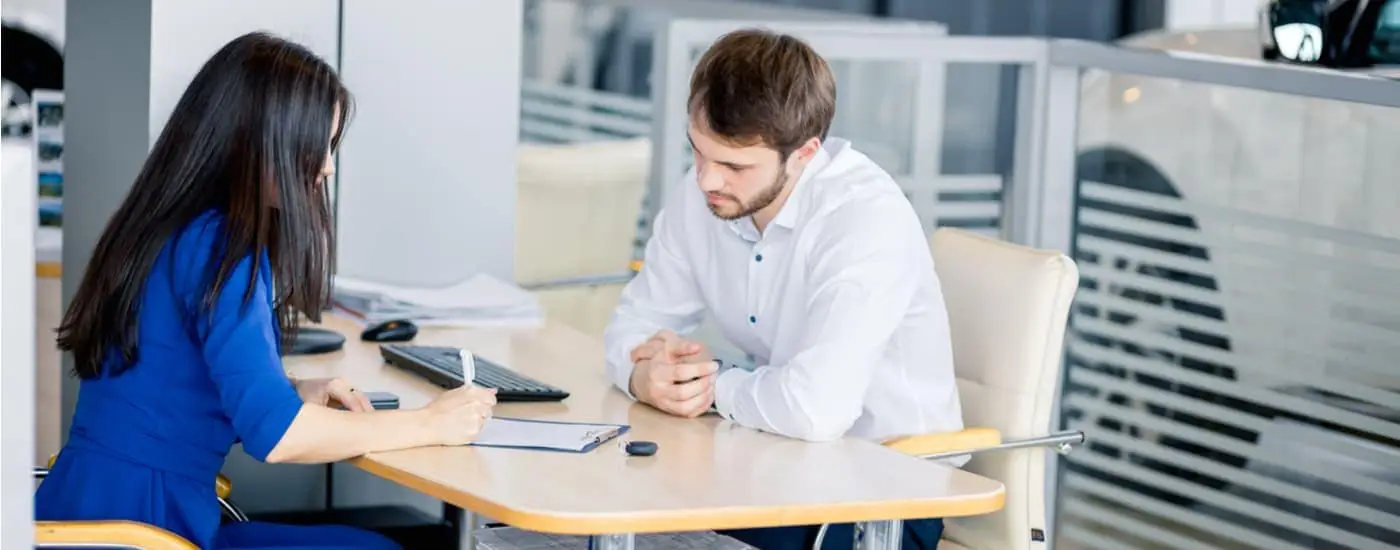 A customer is shown speaking to a saleswoman about how to value their trade.